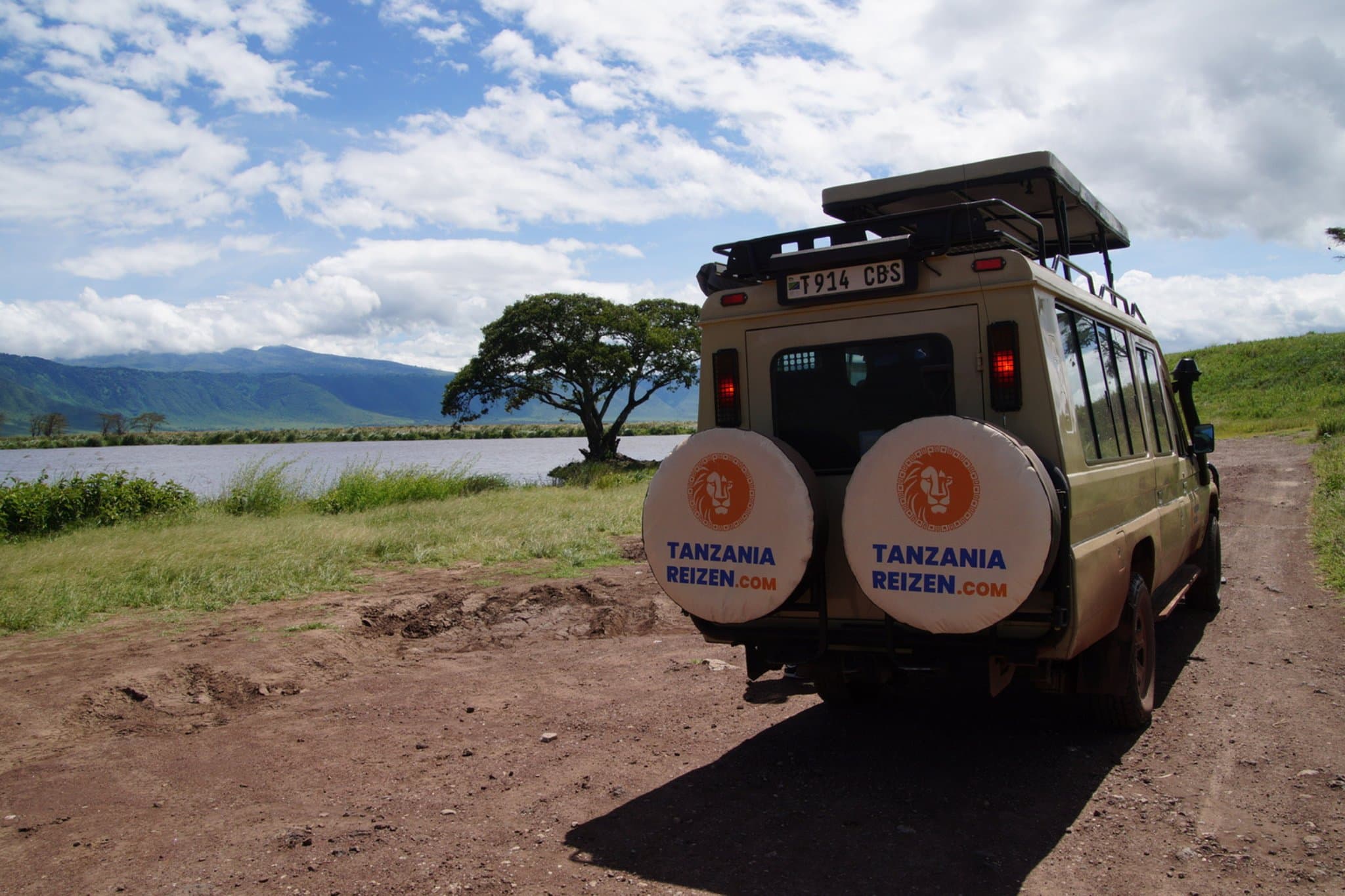 Safariwagen op de kraterbodem van de Ngorongoro bij een ondiep meer