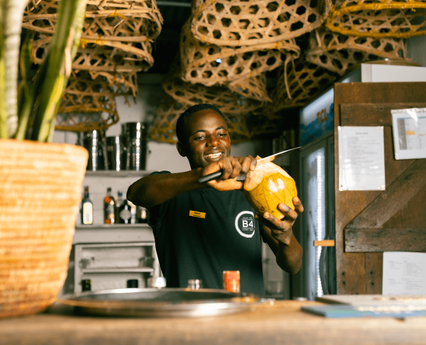 Hotel medewerker met een kokosnoot in zijn hand op Zanzibar